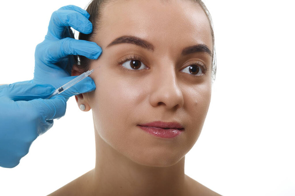 Closeup Beautician Hands doing Facial Skin Lifting Injection To female. Krásná mladá žena tvář a ruce v rukavici s injekční stříkačkou. - Fotografie, Obrázek