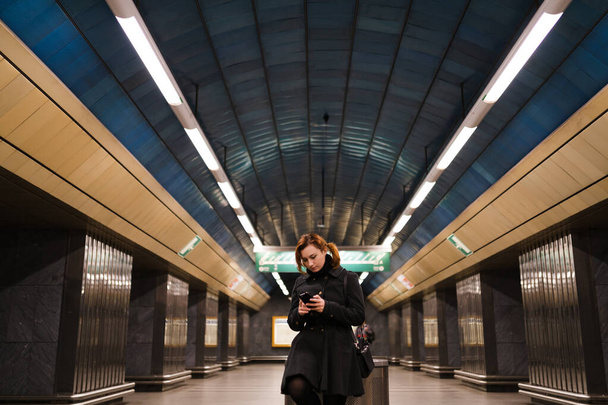 Redhead woman using phone texting in a Prague metro subway - Zdjęcie, obraz