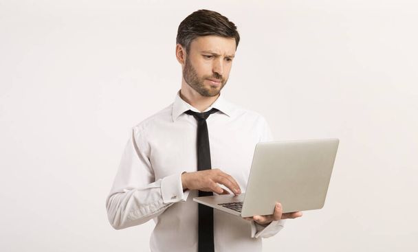 Σοβαρός επιχειρηματίας που εργάζονται σε laptop στέκεται, Studio Shot - Φωτογραφία, εικόνα