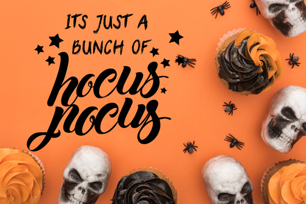 vrchní pohled na cupcakes, dekorativní lebky a pavouky na oranžovém pozadí s ním je jen banda hokus pocus ilustrace - Fotografie, Obrázek