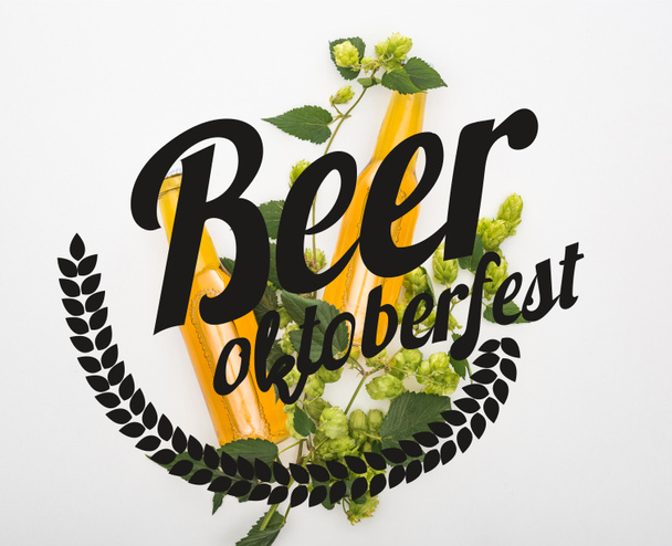 bovenaanzicht van bier in flessen met groene hop op witte achtergrond met bier Oktoberfest illustratie - Foto, afbeelding