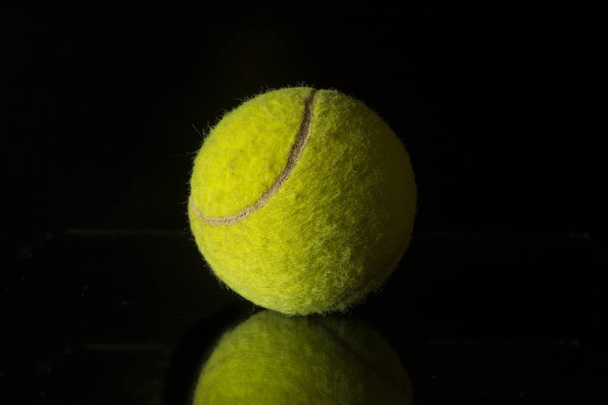 Ball tenisz egy fekete háttér. - Fotó, kép