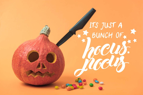 spooky Halloween pumpkin with knife and candies on orange background with hocus pocus illustration - Photo, Image