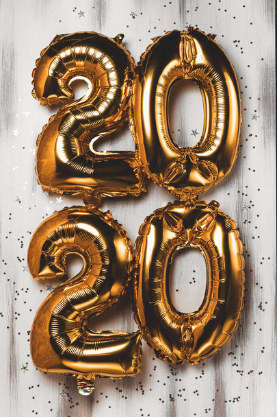 Happy New year 2020 celebration. Bright gold balloons figures, New Year Balloons with glitter stars on wood white background. Christmas and new year celebration. Gold foil balloons 2020 - Foto, Bild