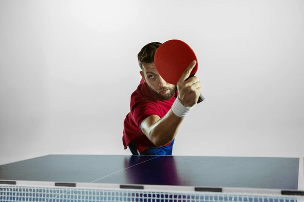 Young man playing table tennis on white studio background - Foto, Imagen