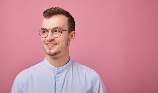 young man in a sky blue shirt and computer glasses posing on pink background  - Photo, image