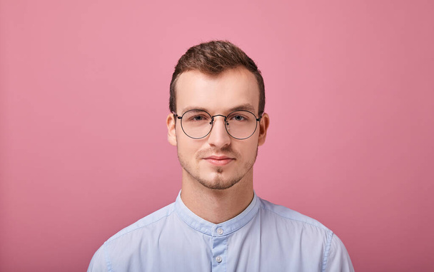 young man in a sky blue shirt and computer glasses posing on pink background  - Fotoğraf, Görsel