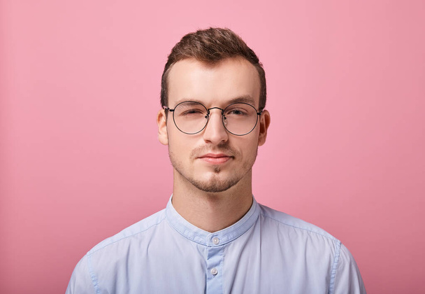young man in a sky blue shirt and computer glasses posing on pink background  - Fotoğraf, Görsel