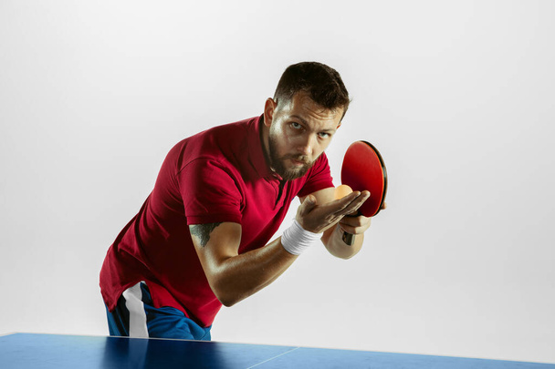 Young man playing table tennis on white studio background - Фото, зображення