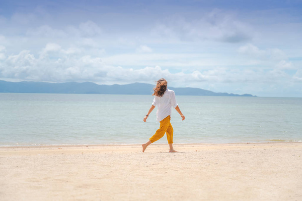 Young beautiful woman in a white shirt and yellow pants runs joy - Foto, imagen