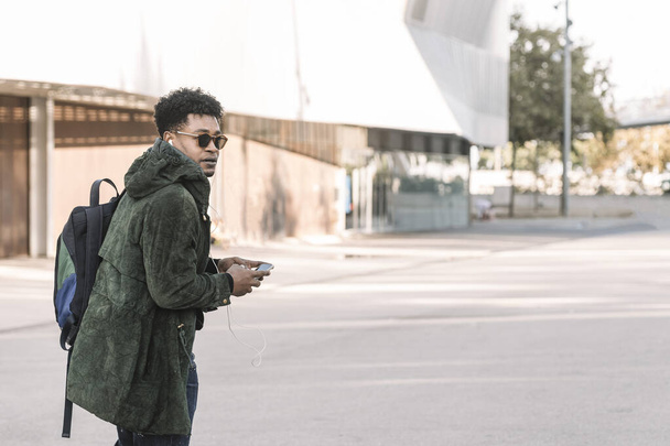 black man with earphones walking by the city - Фото, зображення