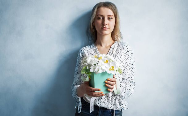 Beautiful brunette girl holding a box with flowers of roses and peonies. - Valokuva, kuva