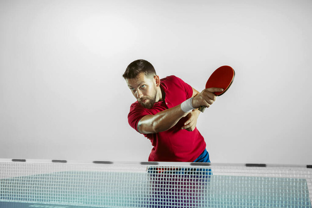 Young man playing table tennis on white studio background - Fotó, kép