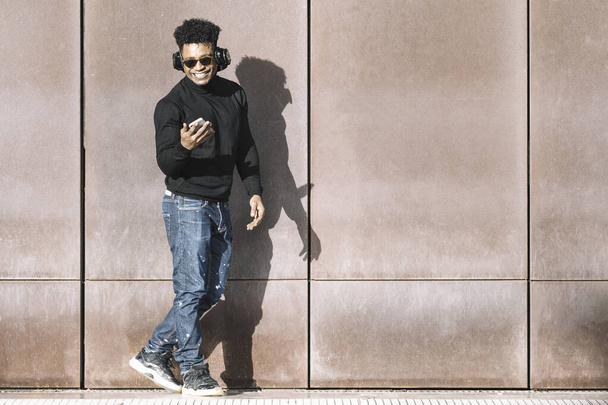 black man smiling and listening music with phone - Foto, Bild
