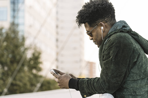 cool young black man texting with a phone - Foto, Bild