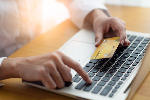 жінка тримає кредитну картку і використовує ноутбук для онлайн-покупки
 - Фото, зображення