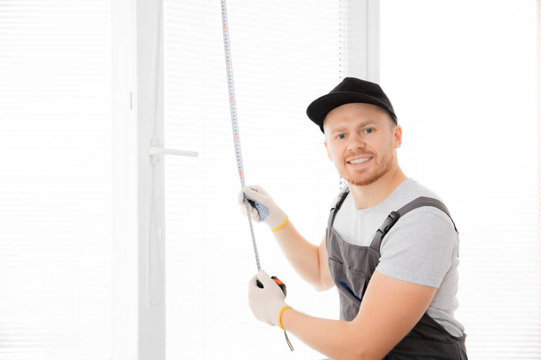 Master worker looking camera and smiling measures upvc window with ruler, installation process - Foto, Imagem