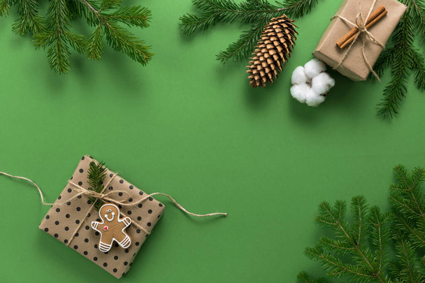 Christmas composition. Gifts, branches of spruce, pine cone, on a green background. Christmas, winter, new year concept. Flat lounger, top view, copy space - 写真・画像