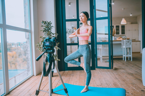 Blogger wearing sport clothing filming yoga tutorial - Foto, immagini