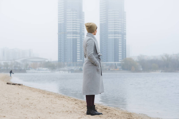 Молода жінка виходить на самоті в сірому пальто
 - Фото, зображення