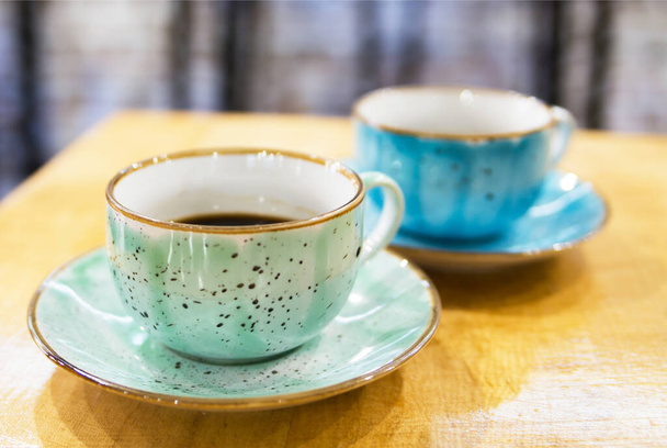 Duas xícaras de café pastel de cor verde e azul em uma mesa de madeira rasgada
 - Foto, Imagem