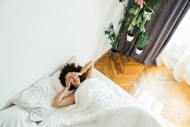 Молодая красивая женщина в постели с белыми простынями яркий свет
 - Фото, изображение