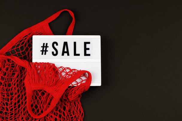 red mesh bag and lightbox with text sale on black background - 写真・画像