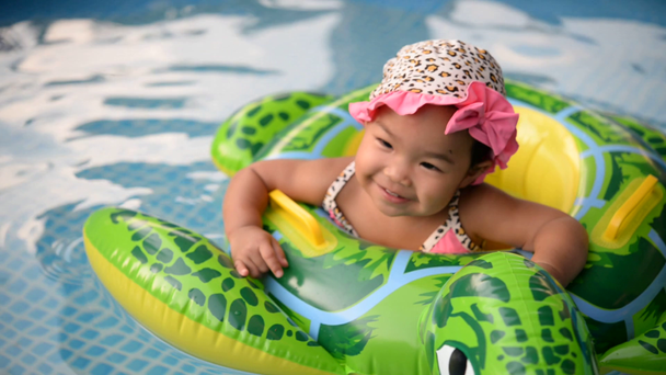 Мила азіатська дівчинка в капелюсі плаває у внутрішній трубці в басейні - Кадри, відео