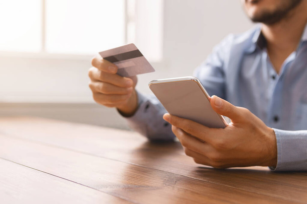 Homme méconnaissable utilisant smartphone et carte de crédit, l'achat de biens en ligne
 - Photo, image
