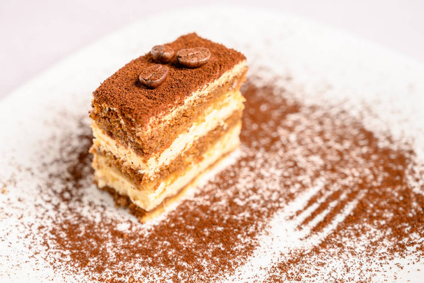 Slice of tiramisu cake decorated with coffee beans on top on a white plate - Photo, Image