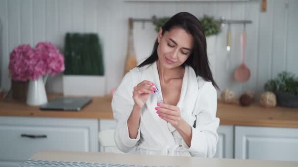 Portrait of young woman applies moisturizing serum to face and does face massage - Felvétel, videó