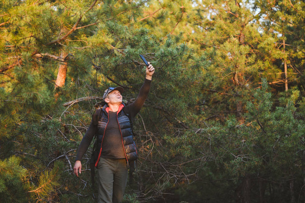Hombre buscando señal para teléfono móvil en el bosque
 - Foto, imagen