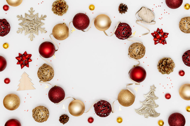 新年とクリスマスのフレーム。赤と黄金のクリスマスの装飾-光沢のあるボール、星、松のコーンと白い紙の背景に装飾的なリボン。トップビュー、フラットレイアウト、コピースペース - 写真・画像