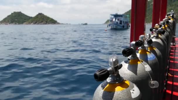 Fila de tanques de oxígeno y equipo de buceo colocado en barco moderno en el océano ondulante cerca de Koh Tao resort, Tailandia. Concepto de deportes turísticos de entretenimiento extremo, aventura y nueva experiencia. - Imágenes, Vídeo