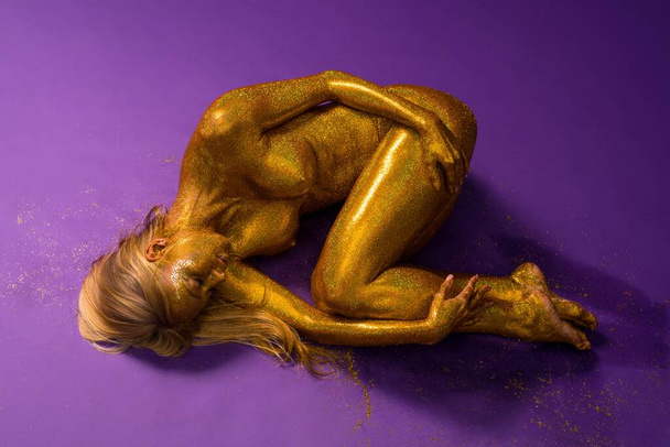 Nude woman with gold bodyart lying on the floor - Foto, Imagem