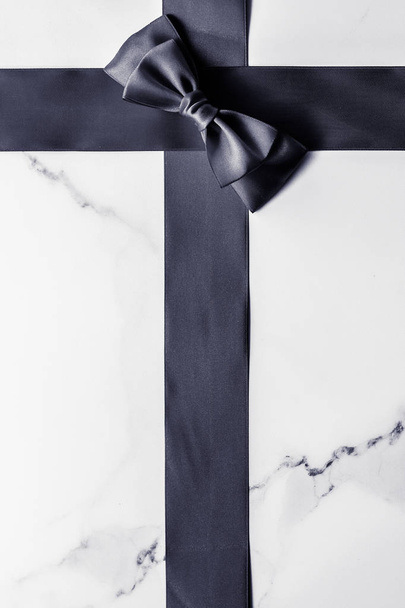 Черная шелковая лента и лук на мраморном фоне, плоский
 - Фото, изображение