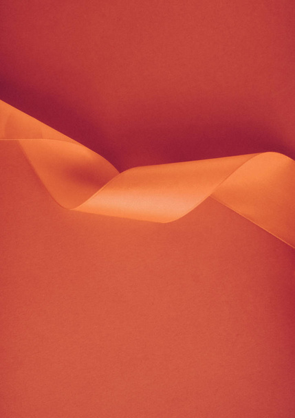 Abstract curly silk ribbon on orange background, exclusive luxur - 写真・画像