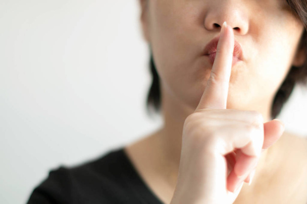 Το κοντινό πρόσωπο των γυναικών χρησιμοποιεί δείκτη αγγίζοντας τα χείλη για την αποστολή ενός σήματος για να είναι ήσυχο ή να κρατήσει μυστικό. - Φωτογραφία, εικόνα