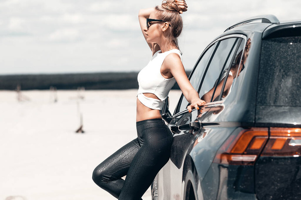 Pretty sexy woman leaning on car on road - Photo, image