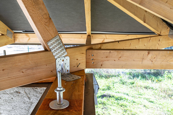 Építés alatt álló családi házon membránnal borított tetőtartók, belülről nézve, látható tetőelemek és ragasztólemezek. - Fotó, kép