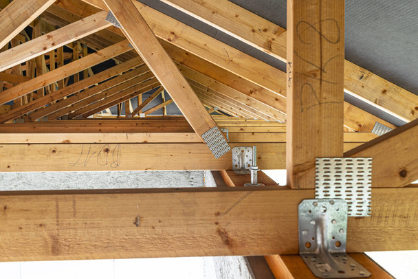 Trusses de techo cubiertos con una membrana en una casa unifamiliar en construcción, vista desde el interior, elementos visibles del techo y placas de armadura
. - Foto, imagen