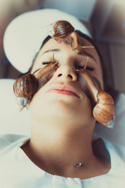 Porträt einer jungen Frau mit einer Schneckenachatina im Gesicht - Foto, Bild