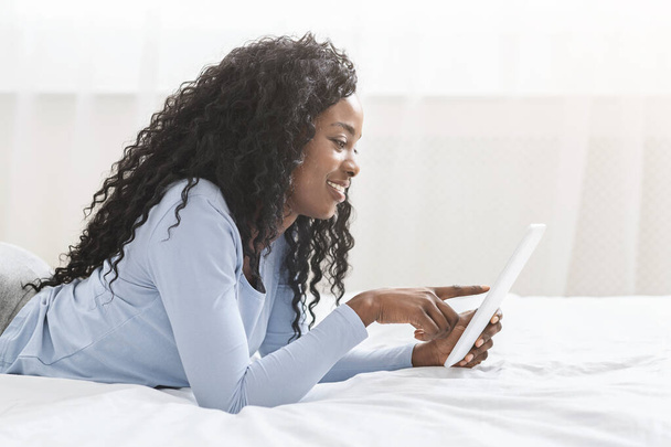Menina afro bonita servindo internet no tablet digital
 - Foto, Imagem