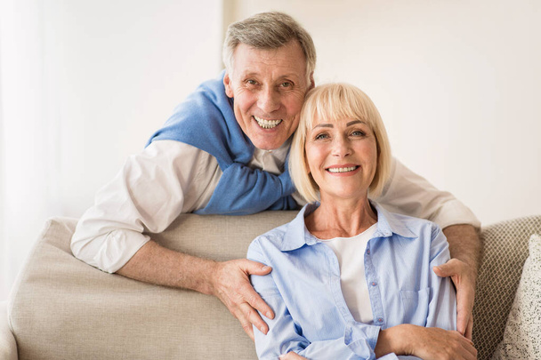 Lovely mature man embracing wife and smiling to camera - Photo, Image