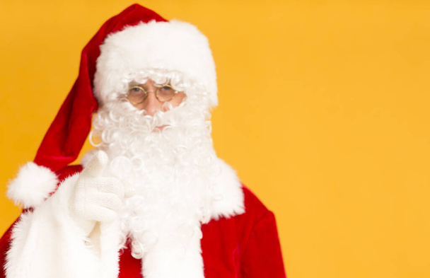 Santa Claus mostrando con el dedo en la cámara sobre naranja
 - Foto, imagen