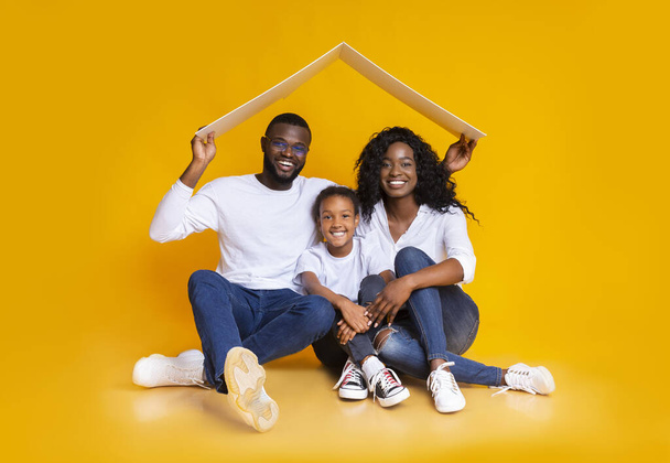 Afro Family Sitting Under Symbolic Roof Thinking About New Home. - Photo, Image