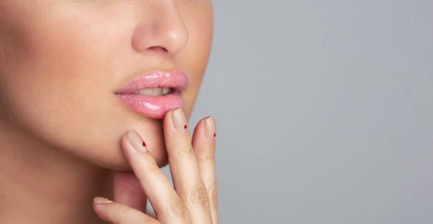 Lips care. Girl applying balm over grey background, closeup - Foto, imagen