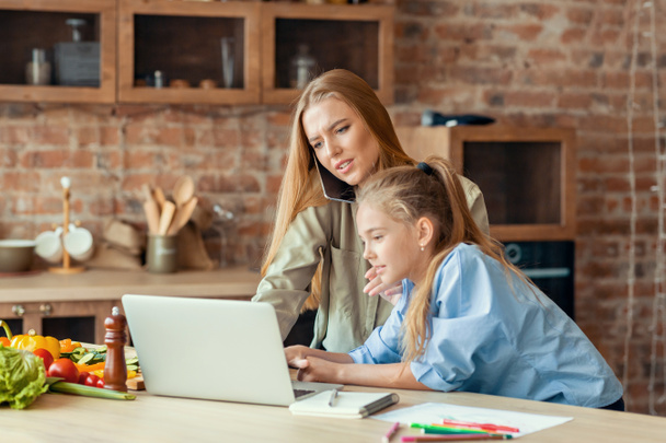 Mädchen unterbricht ihre arbeitende Mutter mit Laptop - Foto, Bild
