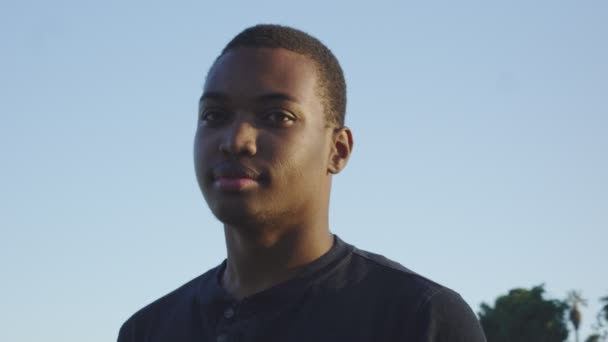 Young african american man looking at camera as it moves around him - Imágenes, Vídeo