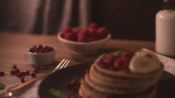 Pancakes with raspberries, banana slices, pomegranate seeds and honey on wooden vintage table. - Video, Çekim